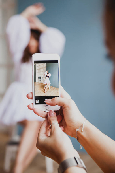 nő kezét, hogy kép fotó videó színpad mögött Fényképezés gyönyörű modell a mobiltelefon színes háttér szöveg  - Fotó, kép