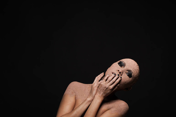 Mujer calva en una máscara de arcilla sobre un fondo negro - Foto, imagen