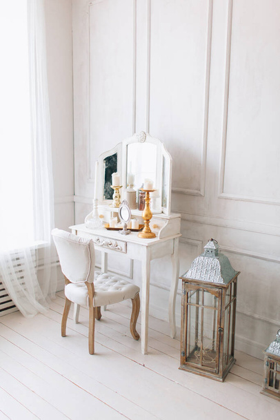 bel intérieur blanc. chambre classique avec plancher en bois murs lumineux avec moulures, chaise coiffeuse avec miroir, décoré avec des éléments dorés - Photo, image