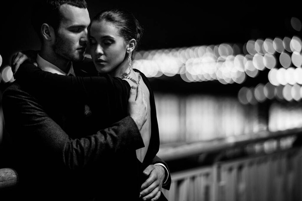 ελκυστικό ζευγάρι με κομψό ντύσιμο αγκαλιάζει έξω τη νύχτα  - Φωτογραφία, εικόνα