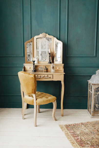 belo interior colorido vintage. quarto clássico com piso de madeira paredes verdes com molduras, vestindo mesa dourada com espelho decorado com elementos, cadeira amarela - Foto, Imagem