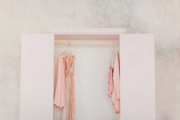 女性の服、オープンドア、装飾、ミラー、バッグ、ハンガー、明るい部屋、コンセプト、花繊細なパステルカラーのシルクドレスのための木製ピンクのワードローブ - 写真・画像