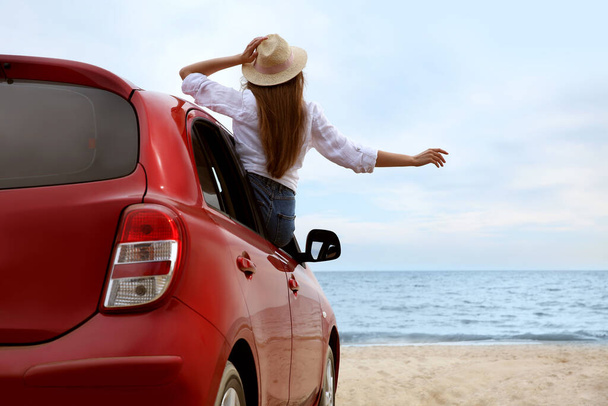 Happy woman leaning out of car window on beach. Summer vacation trip - Foto, Imagem