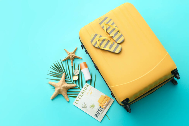 Упакованный чемодан с пляжными аксессуарами на цветном фоне. Концепция путешествия - Фото, изображение