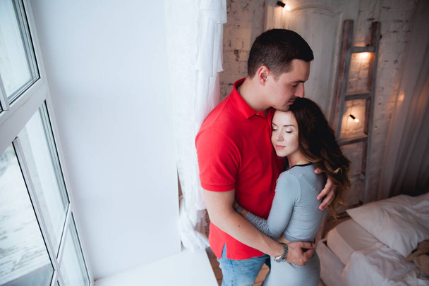 young couple hugging near window at home - Фото, изображение