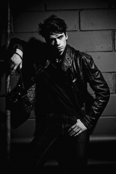 handsome model in leather jacket posing near wall - Fotó, kép