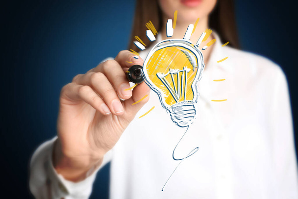 Idea concept. Businesswoman drawing glowing light bulb illustration on virtual screen, closeup - Photo, image