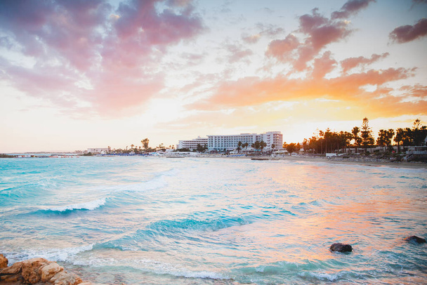 Ein entzückender sanfter Sonnenuntergang an der blauen Meeresküste mit Hotels in Pastelltönen - Foto, Bild