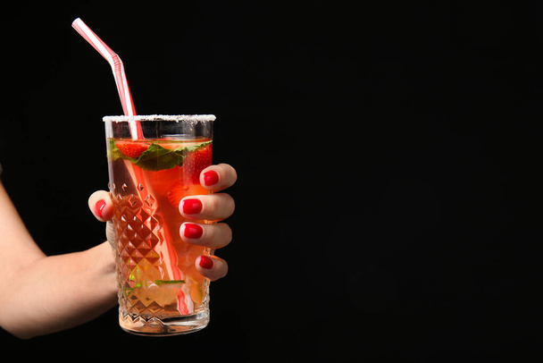 Hand with beautiful manicure holding cocktail on dark background - Foto, Imagen