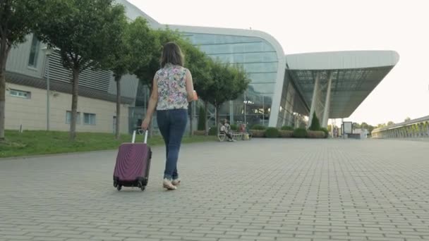 Empresária viajante andando com bagagem para o aeroporto. Menina anda e rola mala saco. Turismo
 - Filmagem, Vídeo