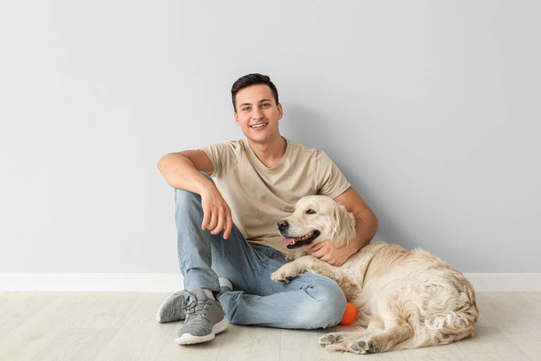 Fiatal férfi aranyos kutya beltérben - Fotó, kép