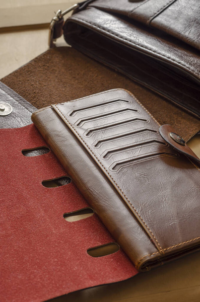 Small leather bag and wallet on wooden table. Open bag and brown leather wallet. Top view at an angle. Selective focus. - Photo, Image