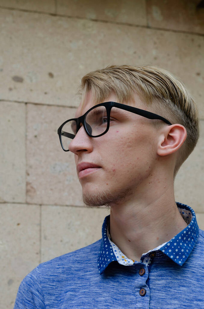 Portrait of stylish young man wearing glasses. Handsome young man in stylish glasses with fashionable hairstyle in fashionable blue shirt posing on the street. Life style. - Photo, Image