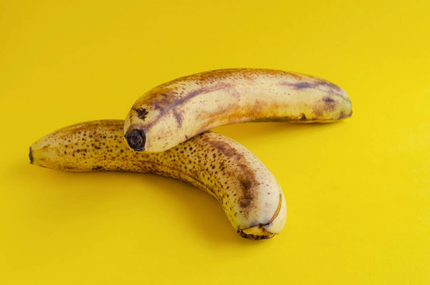 Two overripe bananas with brown spots on yellow background. Ingredients for banana bread, desserts and other dishes. Healthy eating. Selective focus. - Photo, Image