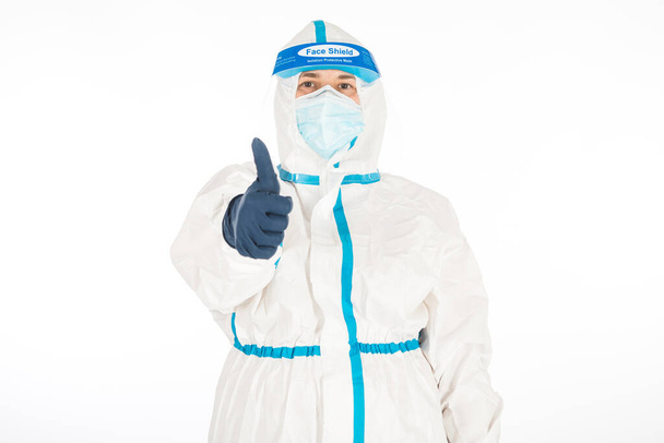 Female doctor wearing PPE to fight coronavirus, thumbs up, on white background. Warrior. COVID medicine concept - Photo, Image