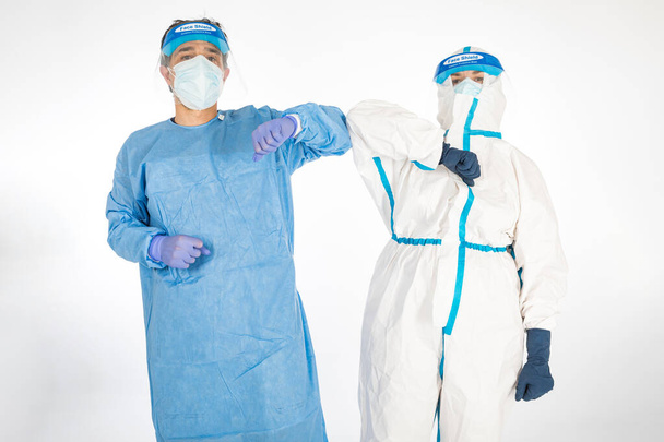 Man wearing PPE and Woman doctor wearing PPE to fight the coronavirus, greeting each other by bumping the elbow, on white background. Warrior. COVID medicine concept - Photo, Image