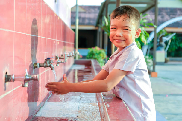 Απαλή εστίαση, φροντίδα υγείας και παιδική έννοια. Ασιάτης παιδί αγόρι πλένει τα χέρια του πριν από το φαγητό και μετά παίζουν τα παιχνίδια στο μπολ πλύσιμο. Ένα αγόρι ηλικίας 5 ετών. - Φωτογραφία, εικόνα