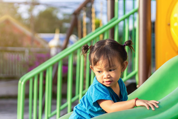 2 yaşındaki bir bebeğin portresi. Mutlu Asyalı kız çocuğu gülümsüyor ve gülüyor. Çocuk parkında sürgülü bar oyuncağıyla oynuyor. Çocuk konseptini öğrenmek ve aktif olmak. - Fotoğraf, Görsel