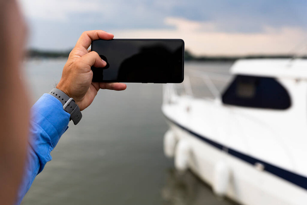Man photographing Yacht with smartphone at the river  - Valokuva, kuva