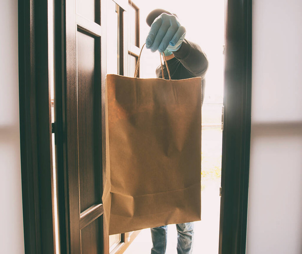 The delivery man gives the bag to the person at his home - Fotoğraf, Görsel