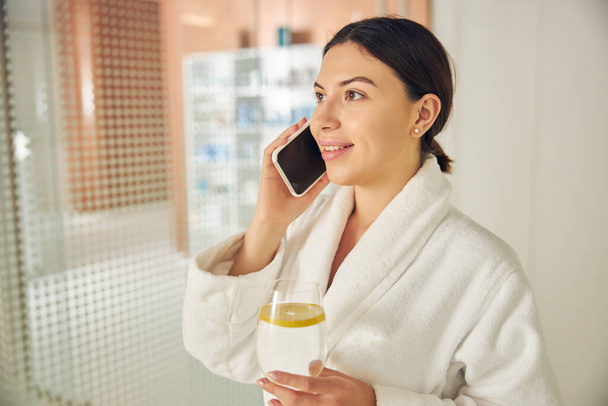 Cliente de spa alegre con un smartphone mirando hacia el futuro - Foto, imagen