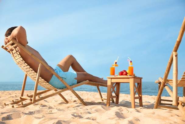 Happy man resting on sunny beach at resort - 写真・画像
