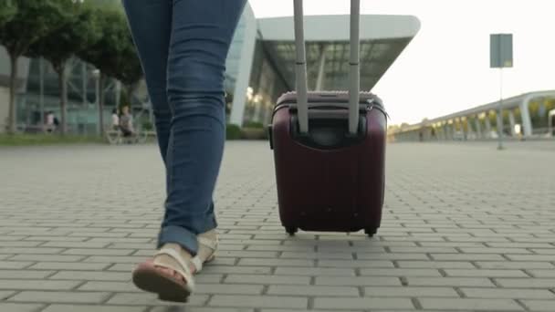 Beine einer Touristin, die mit Gepäck unterwegs ist. Mit Koffertasche auf Rädern die Straße hinunterlaufen - Filmmaterial, Video