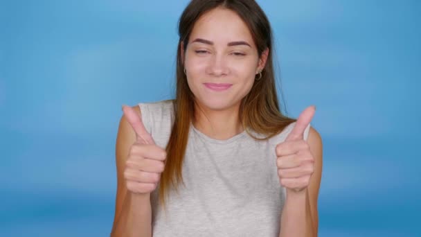 Schöne positive Frau im grauen T-Shirt, die Daumen nach oben zeigt, gefällt und lächelt - Filmmaterial, Video