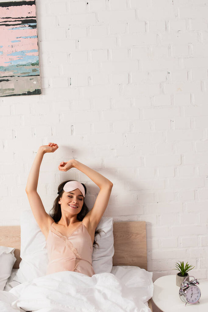 young woman in eye mask stretching in bedroom  - Photo, image