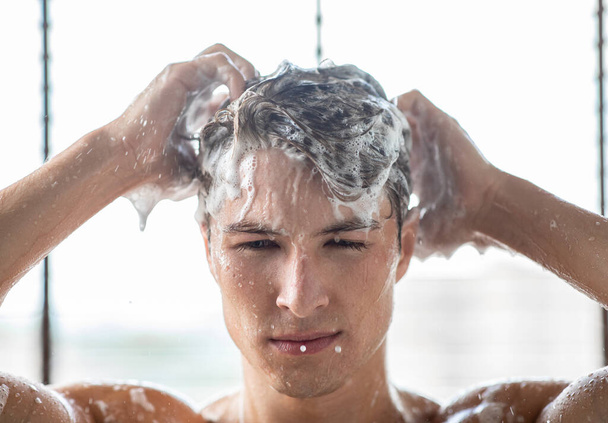 Beau jeune homme qui lave les cheveux avec un shampooing - Photo, image