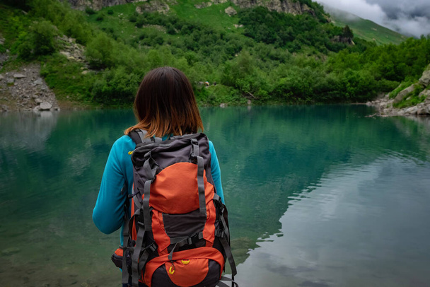 El viajero mira el lago de la montaña. Viajes y concepto de vida activa. Aventura y senderismo en la región de las montañas en el Cáucaso Norte, Dombai, RusiaCáucaso Norte, Dombai, Rusia - Foto, imagen