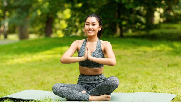 Calma chica asiática meditando en pose de loto durante su clase de yoga al aire libre - Foto, Imagen