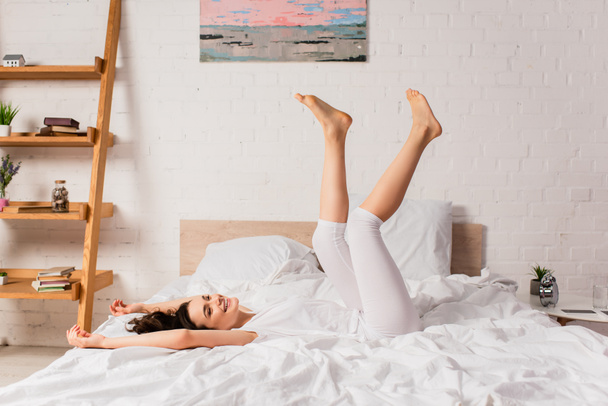 mujer joven y descalza acostada en la cama en casa - Foto, Imagen