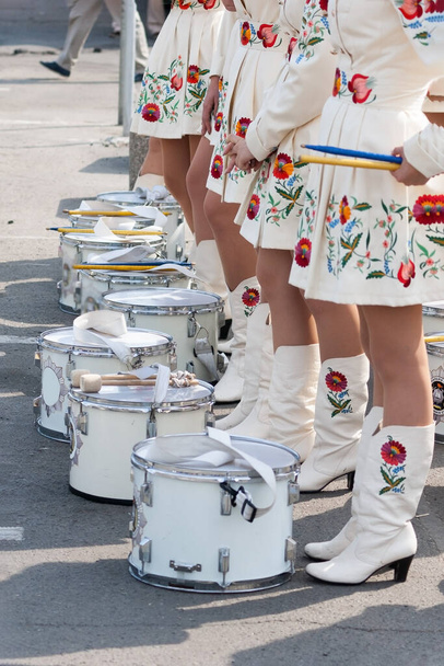 group of drummer girls in white Ukrainian costumes with traditional red ornament, Marching girl band drummers perform, drummers parade - Photo, Image