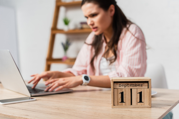 selective focus of wooden cubes with date near woman using laptop  - Фото, изображение