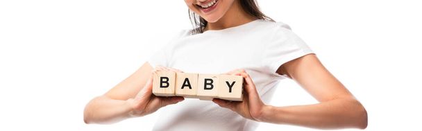 panoramic crop of young pregnant woman in white t-shirt holding wooden cubes with baby lettering isolated on white  - Photo, Image