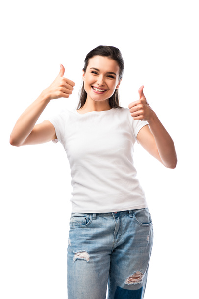 молодая женщина в белой футболке и джинсах показывает большие пальцы вверх изолированы на белом - Фото, изображение