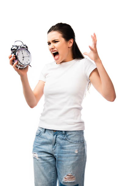 boze vrouw in wit t-shirt houden retro wekker terwijl schreeuwen en gebaren geïsoleerd op wit - Foto, afbeelding