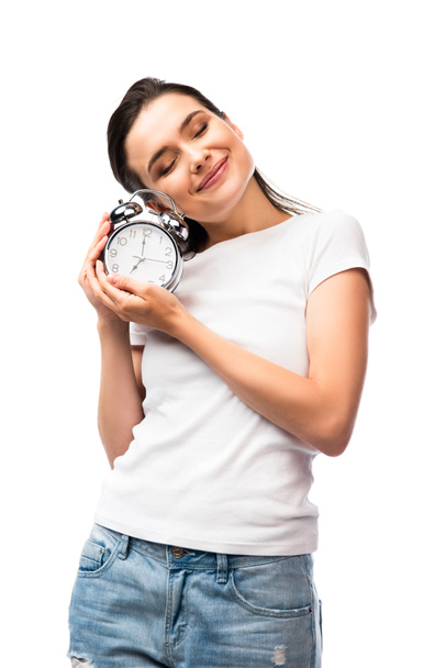woman with closed eyes in white t-shirt holding retro alarm clock isolated on white - Photo, Image