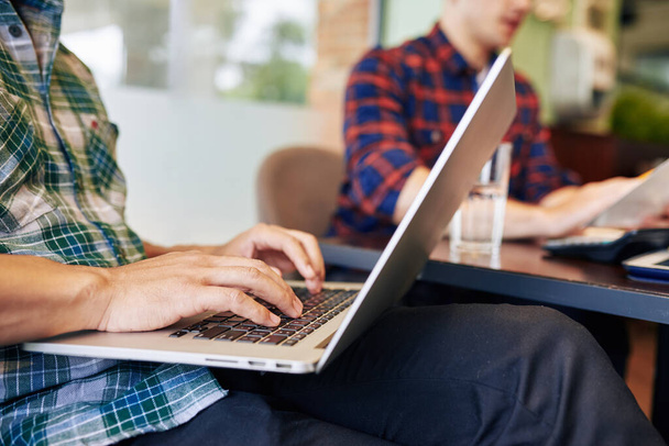 Close-up beeld van universiteitsstudenten die op laptop werken wanneer ze in een lokaal café zitten - Foto, afbeelding