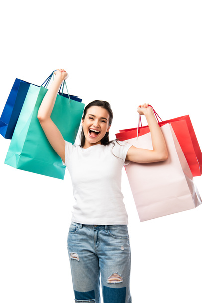 brunette woman with open mouth holding shopping bags isolated on white - Фото, изображение