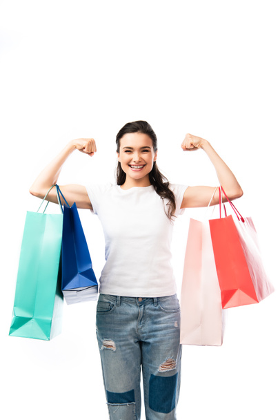 young brunette woman looking at camera and holding shopping bags isolated on white  - 写真・画像