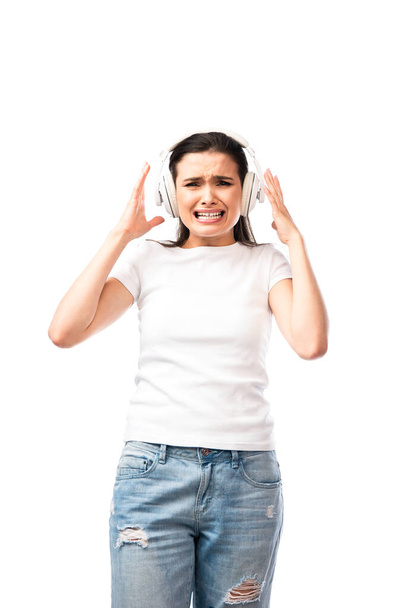 stressed young woman in white t-shirt and wireless headphones isolated on white  - Фото, зображення