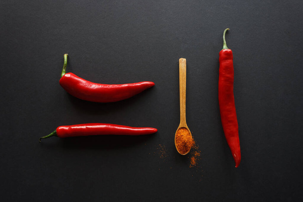 Pods of hot pepper and a spoon with milled pepper on a dark background. Culinary concept. - Fotoğraf, Görsel