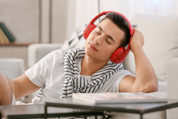 Uykulu genç adam evde müzik dinliyor. - Fotoğraf, Görsel