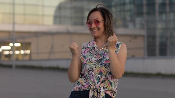 Vreugdevolle toeristische vrouw met ja gebaar met opgeheven armen, enthousiast over succes vieren overwinning - Foto, afbeelding