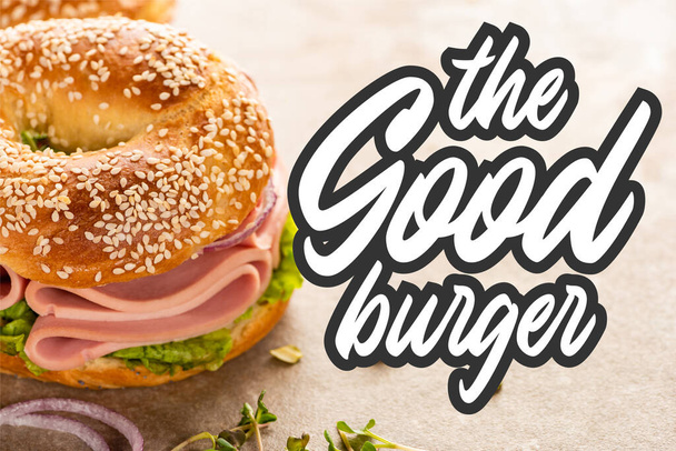 pyszny bajgiel z szynką w pobliżu dobrego napisu burger na teksturowanej powierzchni - Zdjęcie, obraz