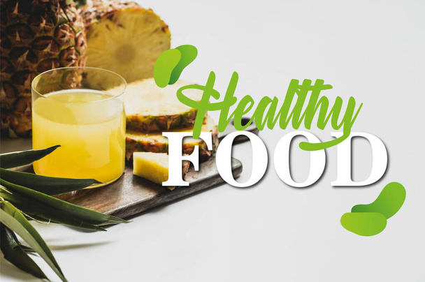 fresh pineapple juice in glass near delicious fruit on wooden cutting board and healthy food lettering on white  - Photo, Image