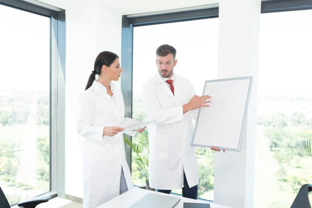 Two doctors holding whiteboard and discussing at office - Foto, Bild