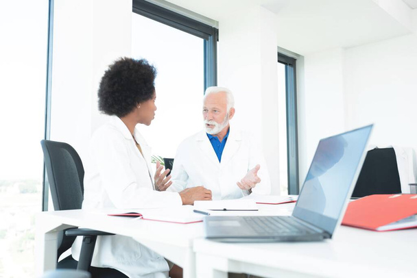 Male and female doctors discussing at office - Foto, imagen